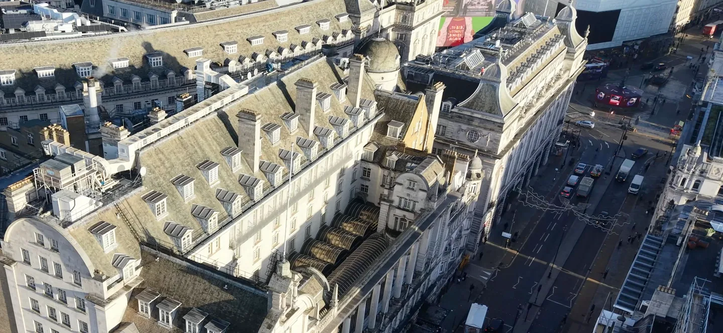 Aerial view of a large period hotel building near Piccadilly Circus, showing its slate mansard roof, dormers and the surrounding streets