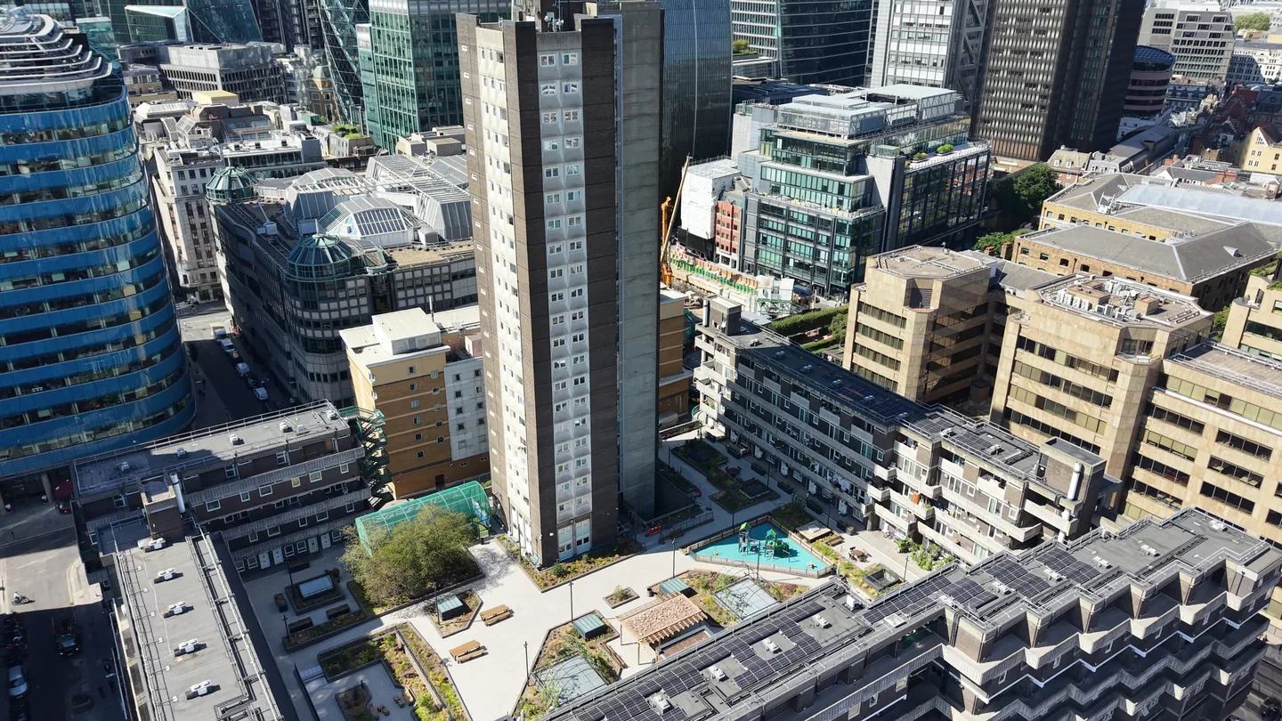 Aerial drone view rising from a London housing estate and tower block to the City of London skyline, with the Gherkin