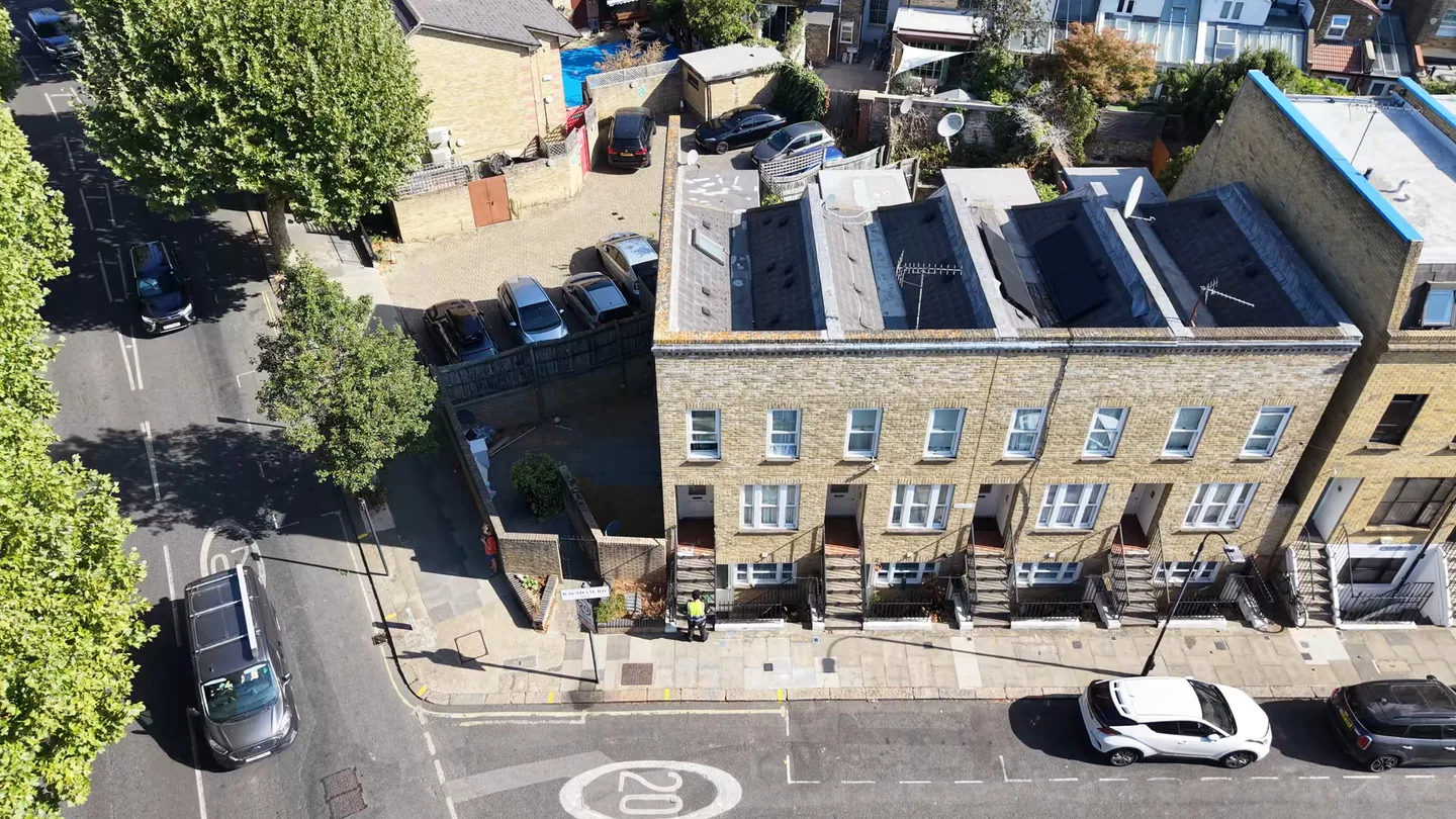 Drone view of a row of London brick terraced houses with slate roofs and solar panels, seen from above the street
