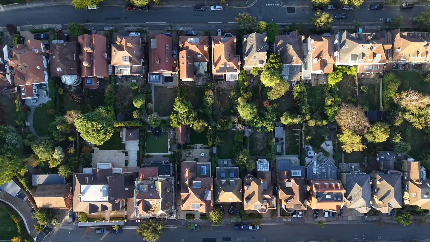 Top-down drone view over rows of London houses, roofs and back gardens